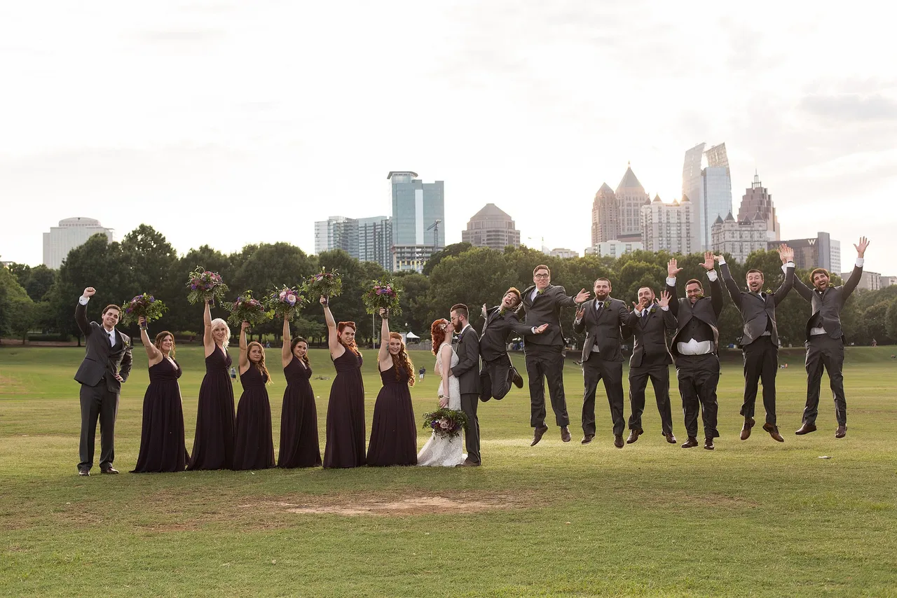 Wedding party jumping for joy with the city skyline in the background.