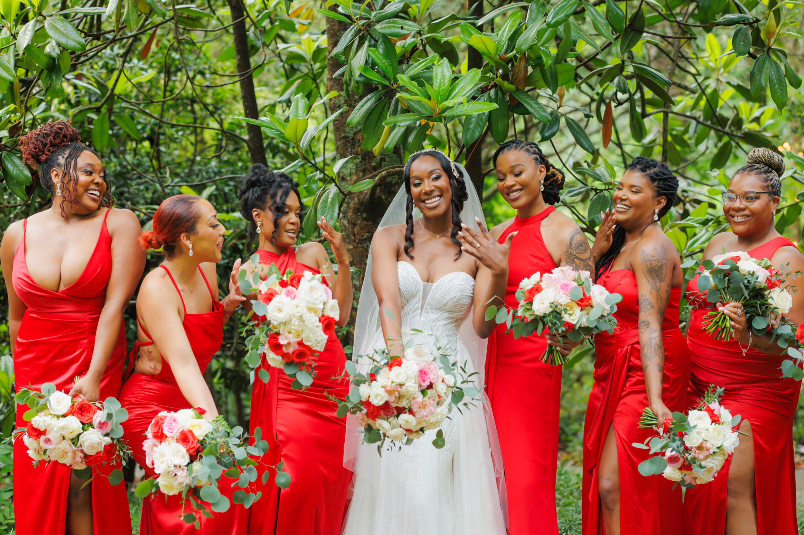 A group of bridesmaids in red dresses and the bride holding vibrant 