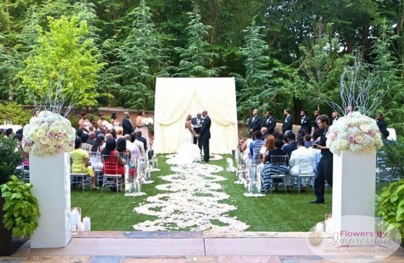 Outdoor wedding ceremony at Villa Christina in Atlanta with floral arrangements of pink and white roses, ivory draped altar, and spiral petal aisle.