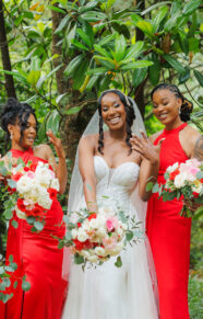 A group of bridesmaids in red dresses and the bride holding vibrant 
