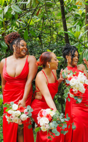 A group of bridesmaids in red dresses and the bride holding vibrant 