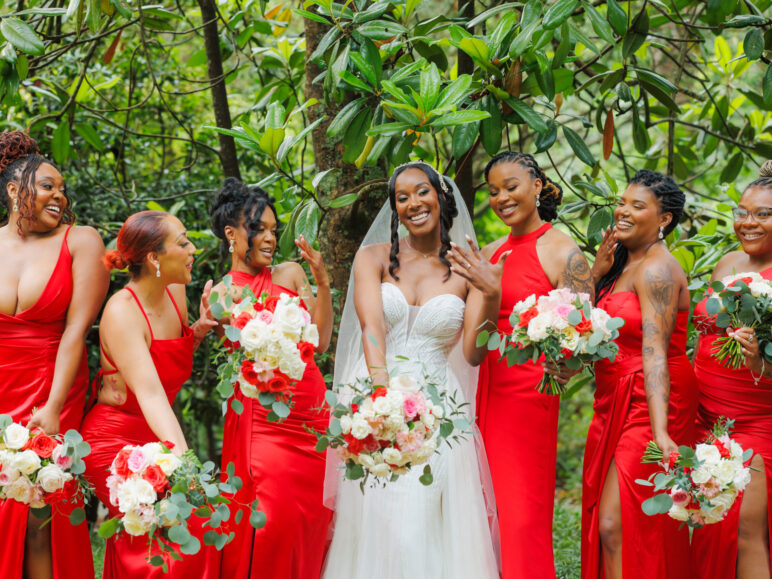 A group of bridesmaids in red dresses and the bride holding vibrant 