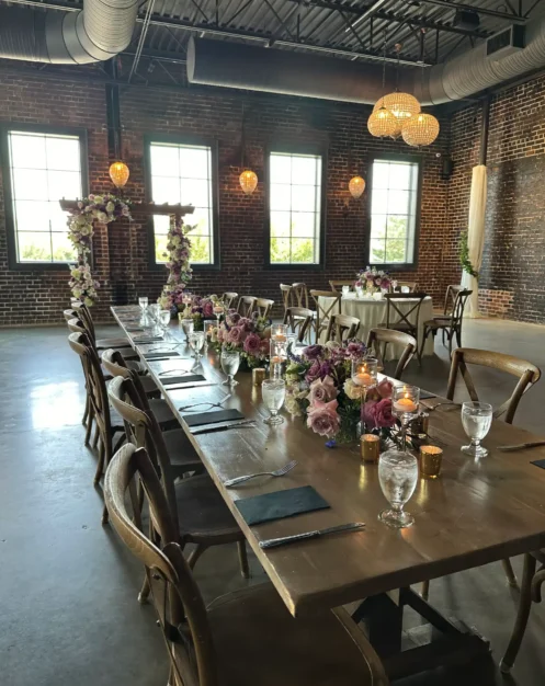 Elegant reception table setting with floral centerpieces and candlelight at an Autumn wedding in a rustic indoor venue.