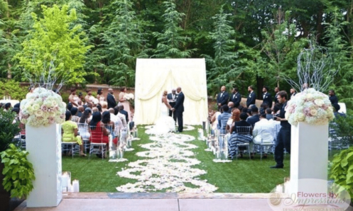 Outdoor wedding ceremony at Villa Christina in Atlanta with floral arrangements of pink and white roses, ivory draped altar, and spiral petal aisle.