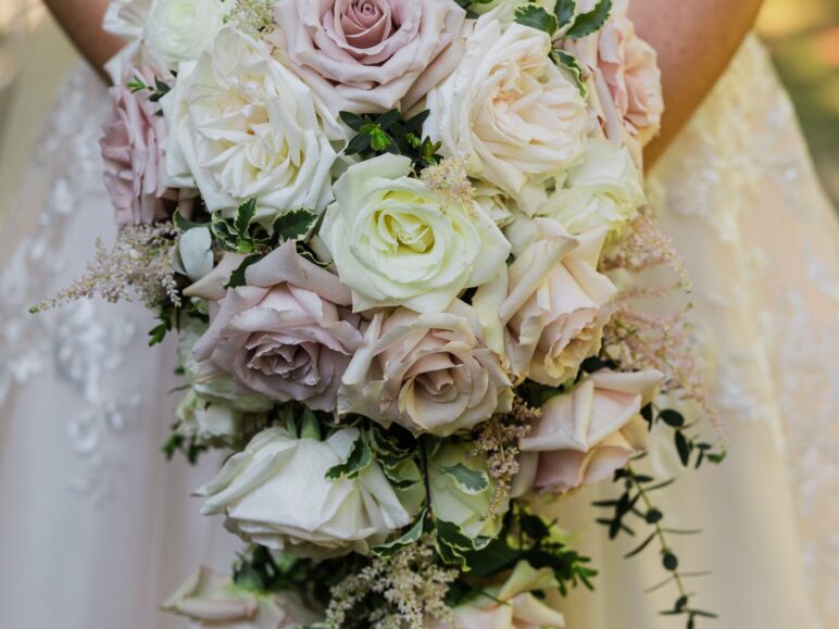 A close-up of a beautiful bride bouquet held by a bride in an elegant lace wedding dress.