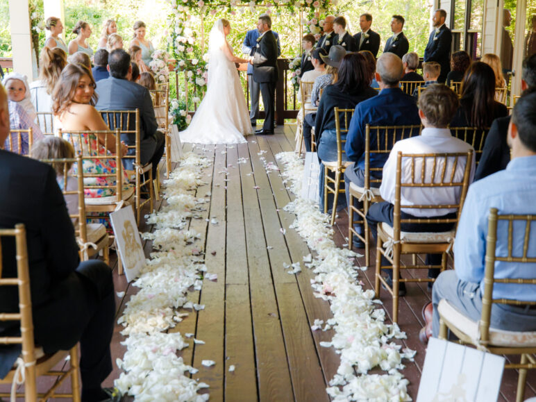 Wedding ceremony with guests and floral arrangements.