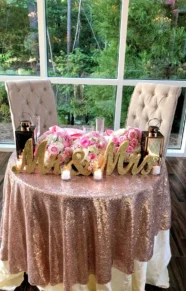 Sweetheart table decor with pink and white floral centerpiece, lanterns, and 