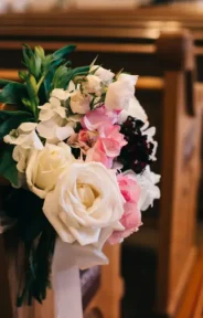 Floral arrangement attached to a pew for wedding ceremony decor.