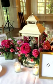 Guest wedding table arrangement with lantern and vibrant floral centerpiece.