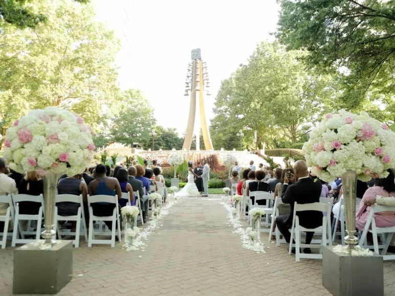 Outdoor wedding ceremony with floral aisle decorations and large flower arrangements.