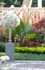 Elegant outdoor wedding ceremony decor with large floral arrangements and a fountain backdrop
