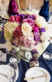 Guest wedding table arrangement with vibrant floral centerpiece and elegant table setting.