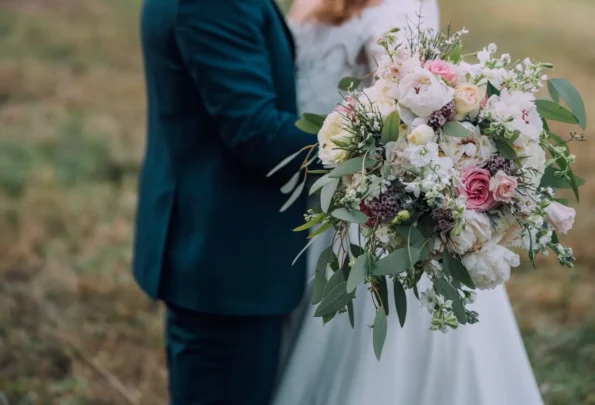 Bride and groom share a kiss while holding a bouquet of flowers