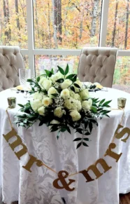 wedding table centerpiece with white roses and green leaves