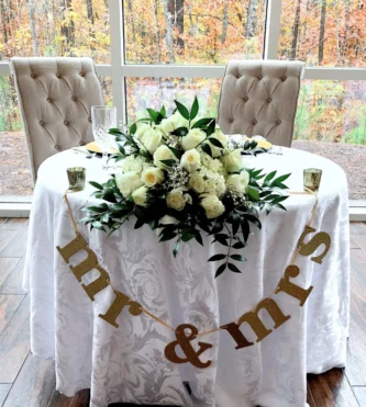 wedding table centerpiece with white roses and green leaves