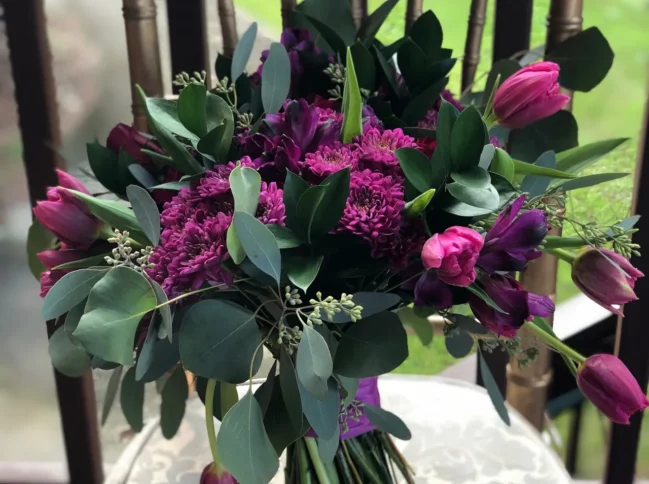 deep purple tulips and vibrant magenta blooms, accented with lush greenery and delicate filler flowers.