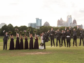 Wedding party jumping for joy with the city skyline in the background.